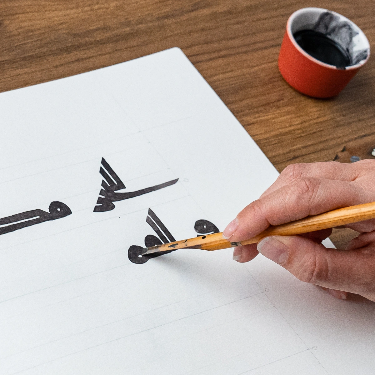 A reed pen drawing a Kufic letterform